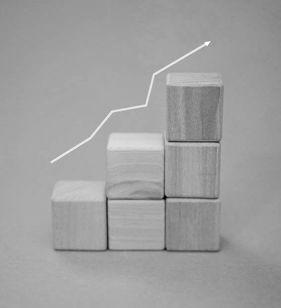 Növekedést mutató grafikon fakockákon, ami a weboldal és a hirdetések összehangolását, valamint az olcsóbb kattintási költségeket eredményező ökoszisztémát mutatja.