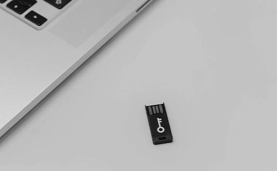 Biztonsági USB kulcs egy laptop mellett, ami az adatvesztés elleni heti automatikus biztonsági mentést és a weboldal hiba esetén történő gyors visszaállítását szimbolizálja.